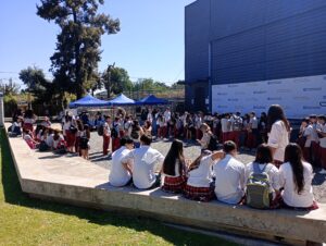 estudiantes de secundaria sentados en gradas del campus y otrxs en la zona de la feria gastronómica en la zona de gazebos